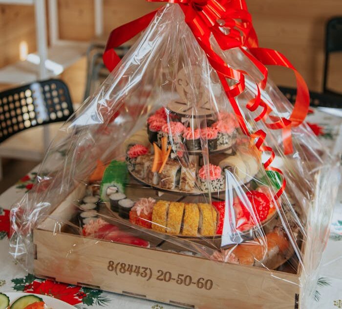 Various delicious food served in gift wrapping with red ribbon on table at daylight